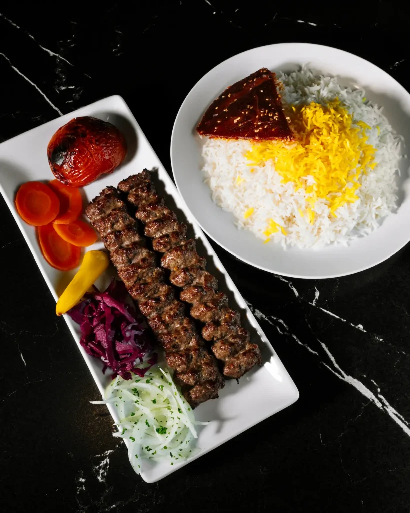 Brochettes de kebab koobideh avec riz safrané et tomates grillées